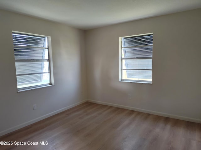 spare room with baseboards, a wealth of natural light, and light wood-type flooring