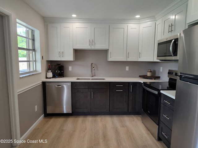 kitchen with light countertops, stainless steel appliances, white cabinetry, and a sink