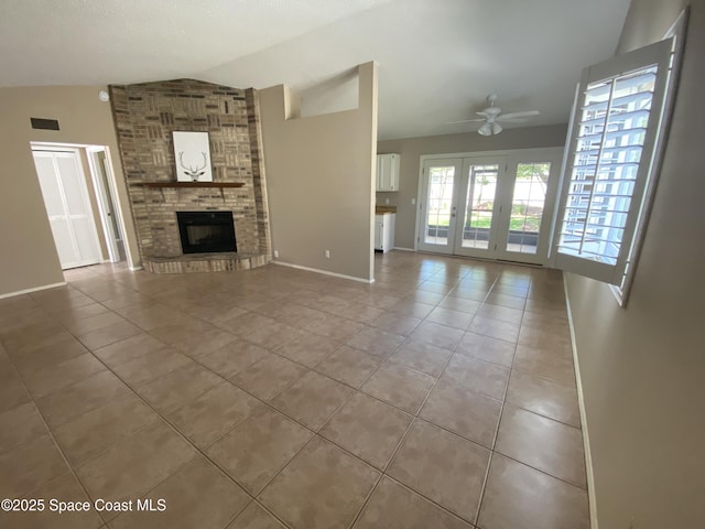 unfurnished living room with vaulted ceiling, tile patterned flooring, a ceiling fan, a fireplace, and baseboards