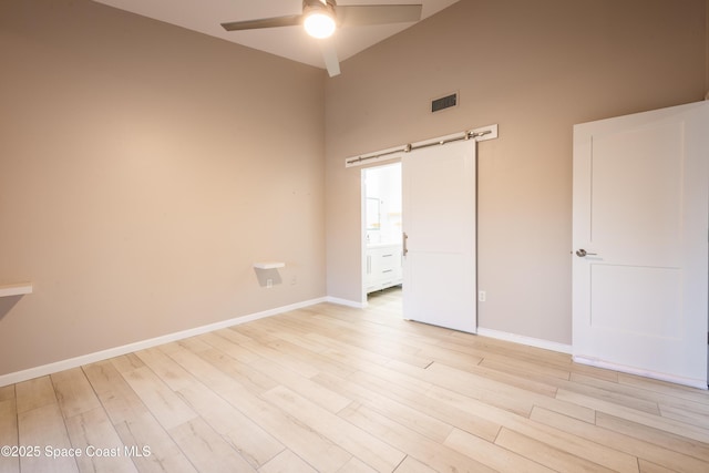 3564 Muirfield Dr Unit 4, Titusville, FL 32780 - empty room featuring ceiling fan, light wood-type flooring, baseboards, a barn door, and a towering ceiling