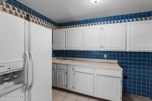 clothes washing area with light tile patterned floors, tile walls, and a sink