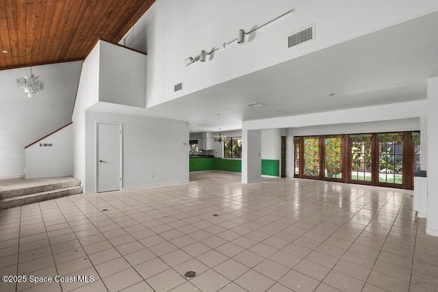 unfurnished living room featuring visible vents, wooden ceiling, tile patterned flooring, and a towering ceiling