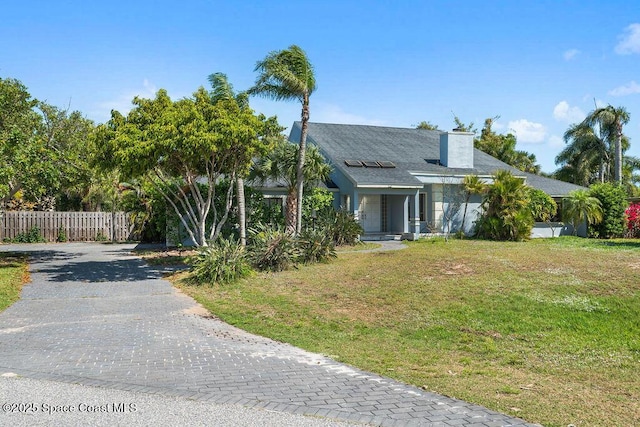 obstructed view of property with fence, a chimney, driveway, and a front lawn