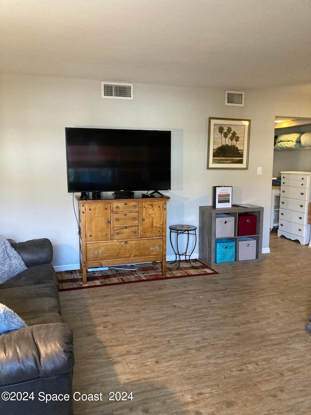 living area featuring baseboards, visible vents, and wood finished floors