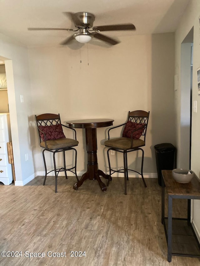 living area with baseboards, ceiling fan, and wood finished floors