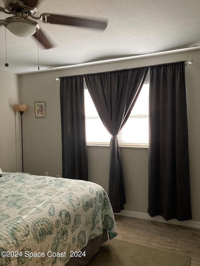bedroom with multiple windows, a ceiling fan, and wood finished floors