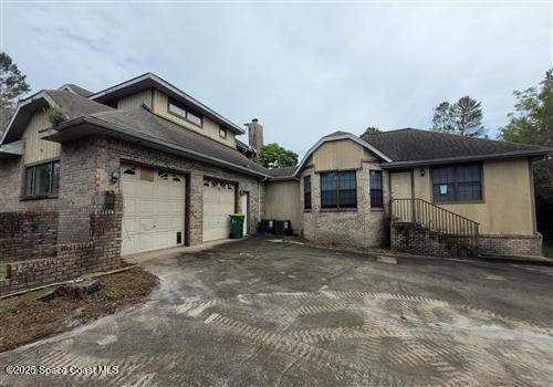 view of front of house featuring brick siding, a garage, a chimney, and aphalt driveway