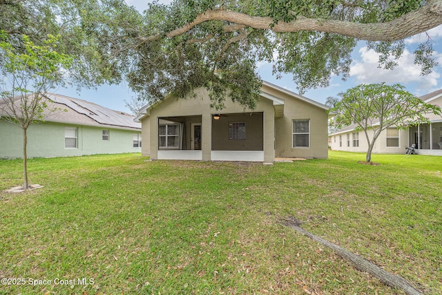 3873 San Miguel Ln, Rockledge, FL 32955 - rear view of property with a sunroom, a lawn, and stucco siding