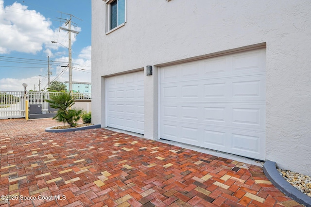 garage featuring fence and decorative driveway