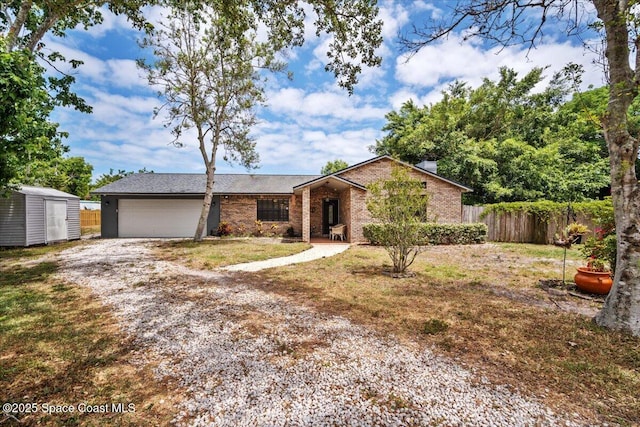 512 Palmetto Dr, Melbourne, FL 32935 - ranch-style house featuring driveway, a storage shed, brick siding, fence, and an attached garage