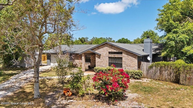 512 Palmetto Dr, Melbourne, FL 32935 - view of front facade with brick siding, fence, and a chimney