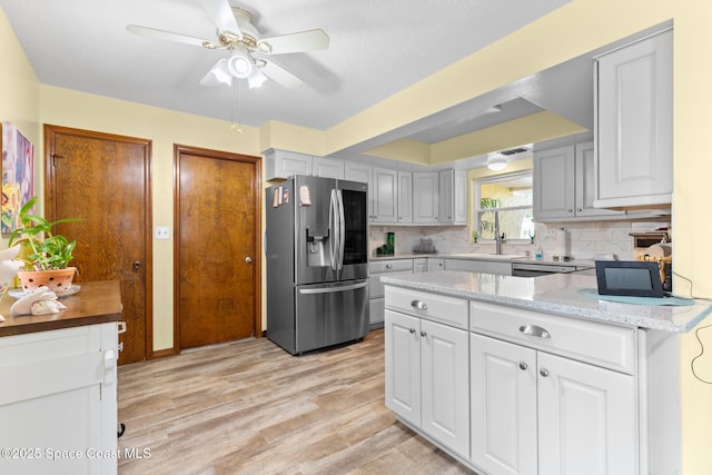 550 E Merrimac Dr, Merritt Island, FL 32952 - kitchen with stainless steel refrigerator with ice dispenser, white cabinets, ceiling fan, backsplash, and light wood-style floors