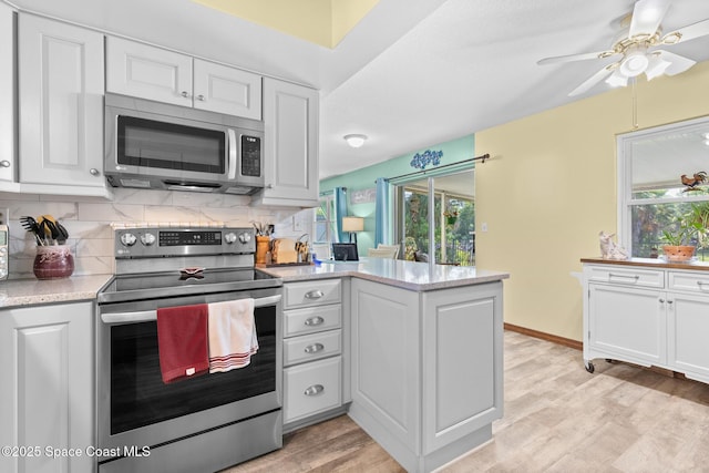 550 E Merrimac Dr, Merritt Island, FL 32952 - kitchen featuring a peninsula, light wood-style floors, white cabinets, backsplash, and appliances with stainless steel finishes