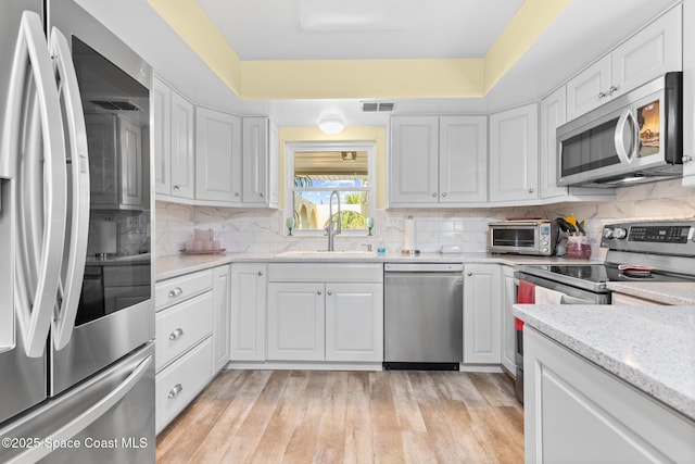 550 E Merrimac Dr, Merritt Island, FL 32952 - kitchen with a toaster, stainless steel appliances, white cabinetry, visible vents, and tasteful backsplash
