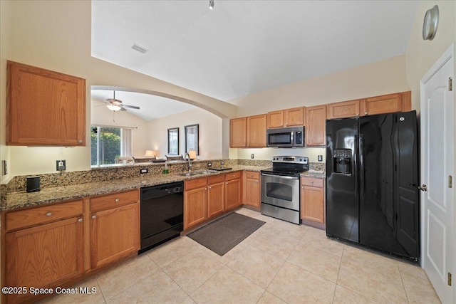 kitchen with black appliances, vaulted ceiling, dark stone counters, a sink, and light tile patterned floors