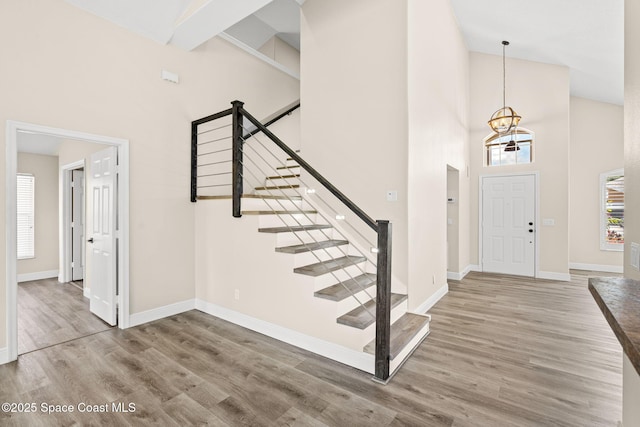 1050 Olde Bailey Ln, Melbourne, FL 32904 - foyer entrance with high vaulted ceiling, a chandelier, wood finished floors, baseboards, and stairway