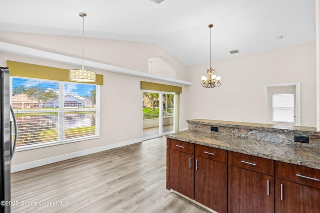1050 Olde Bailey Ln, Melbourne, FL 32904 - kitchen with lofted ceiling, freestanding refrigerator, light wood-style flooring, light stone countertops, and a chandelier