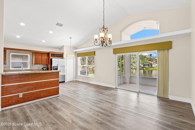 1050 Olde Bailey Ln, Melbourne, FL 32904 - kitchen featuring stainless steel fridge, brown cabinetry, hanging light fixtures, light countertops, and recessed lighting
