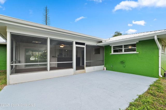 back of house with a sunroom, a patio, metal roof, and stucco siding