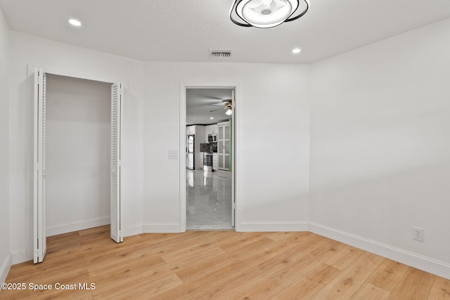 unfurnished bedroom with light wood-style flooring, baseboards, recessed lighting, and a closet