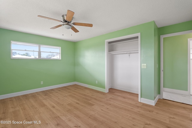 unfurnished bedroom with a closet, light wood-style flooring, baseboards, a textured ceiling, and ceiling fan