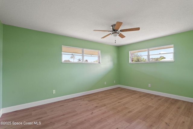unfurnished room with a ceiling fan, light wood-type flooring, baseboards, and a textured ceiling