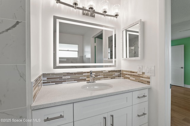 bathroom with tasteful backsplash, vanity, and wood finished floors