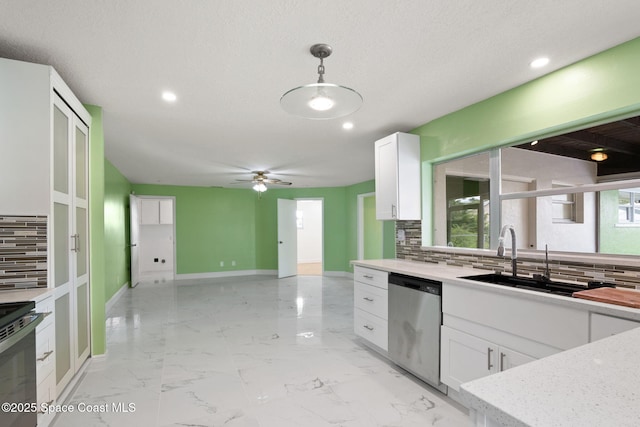 kitchen with stainless steel dishwasher, a sink, tasteful backsplash, white cabinetry, and baseboards