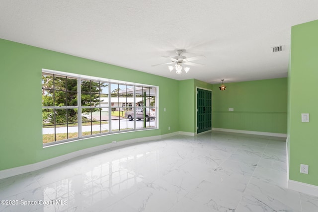 unfurnished room with baseboards, a ceiling fan, marble finish flooring, and a textured ceiling