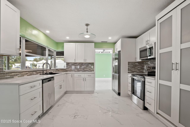 kitchen featuring stainless steel appliances, backsplash, light marble finish floors, white cabinets, and recessed lighting