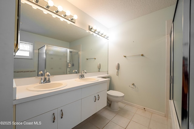 bathroom featuring double vanity, a sink, a textured ceiling, and a shower with shower door