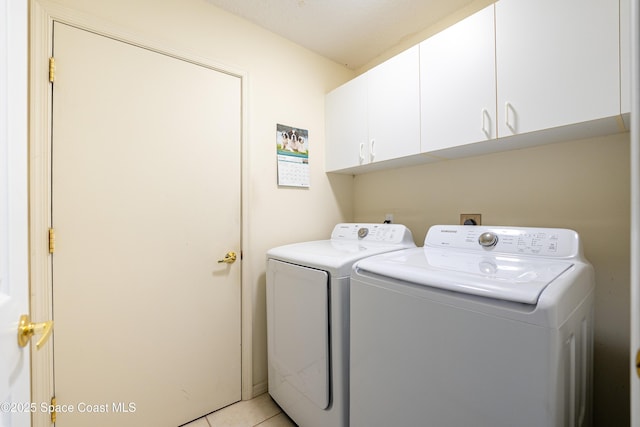 washroom with cabinet space, light tile patterned floors, and washing machine and clothes dryer