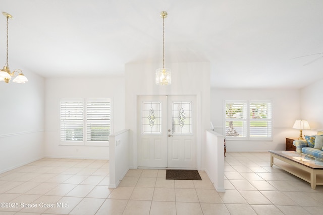 entryway with baseboards, a notable chandelier, and light tile patterned floors