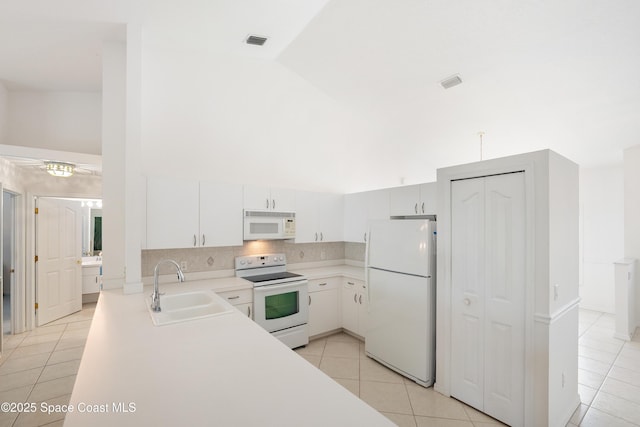 kitchen featuring visible vents, light tile patterned flooring, white appliances, light countertops, and a sink