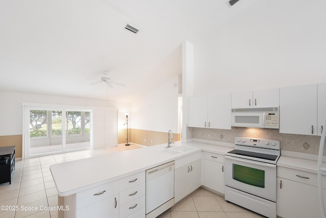 kitchen featuring tasteful backsplash, a sink, light tile patterned floors, a peninsula, and white appliances