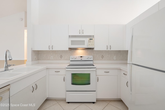 kitchen with light tile patterned flooring, white appliances, white cabinetry, tasteful backsplash, and a sink