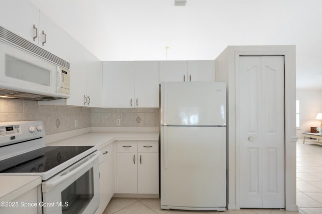 kitchen with decorative backsplash, light tile patterned floors, white appliances, and light countertops