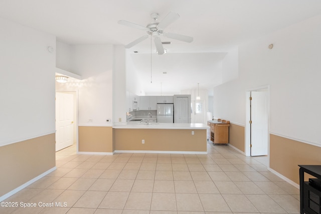 kitchen featuring a ceiling fan, a sink, light countertops, freestanding refrigerator, and a peninsula