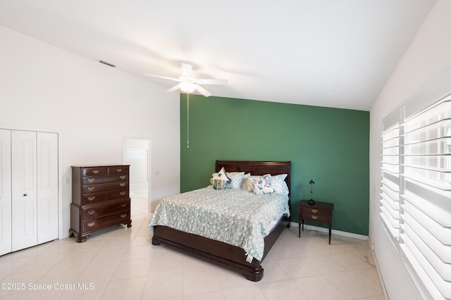 bedroom with a closet, lofted ceiling, an accent wall, ceiling fan, and light tile patterned floors