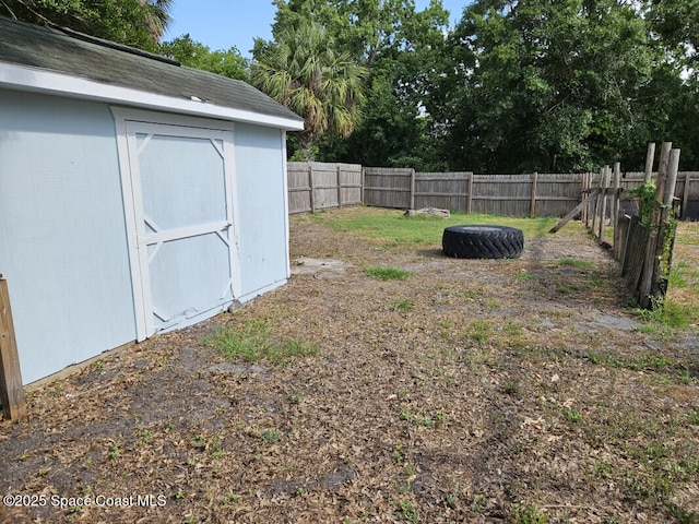 view of yard with a fenced backyard, an outbuilding, and a storage shed