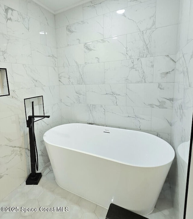bathroom with marble finish floor, a freestanding tub, and tile walls