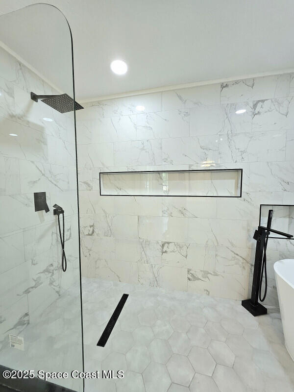full bathroom featuring a freestanding tub and a marble finish shower