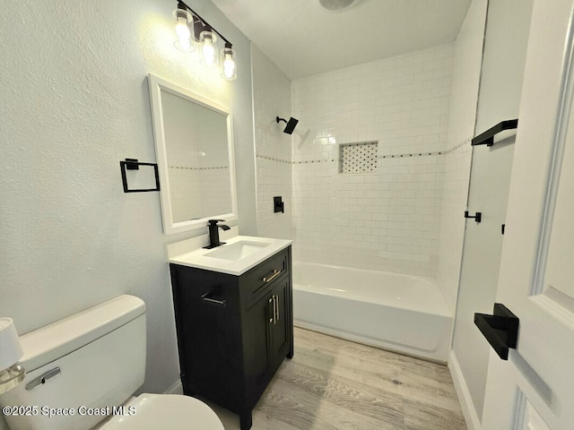 bathroom featuring vanity, toilet, wood finished floors, and bathtub / shower combination