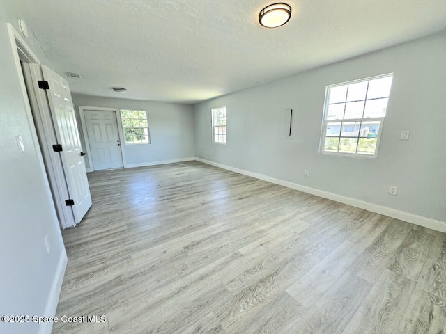 empty room featuring baseboards, visible vents, and light wood-type flooring