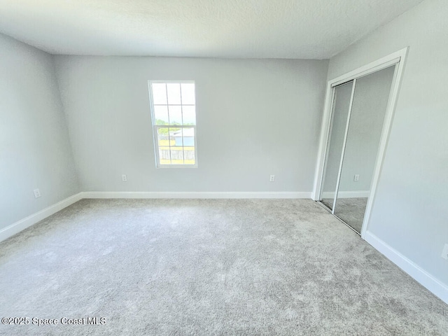 unfurnished bedroom with a closet, a textured ceiling, baseboards, and carpet floors