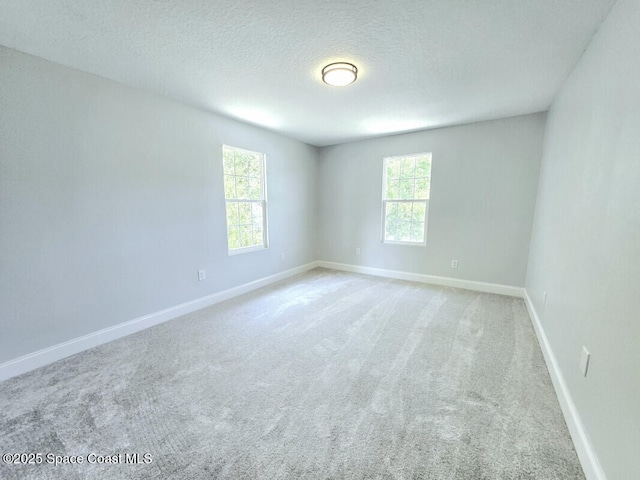 spare room with a textured ceiling, baseboards, and carpet