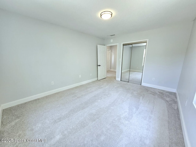 unfurnished bedroom featuring a closet, baseboards, and light carpet