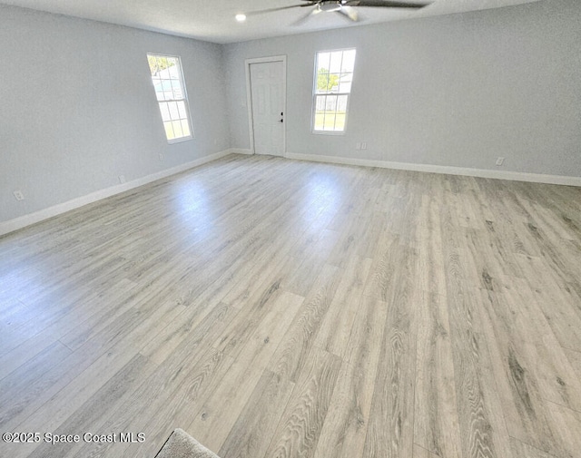 empty room featuring plenty of natural light, a ceiling fan, and wood finished floors