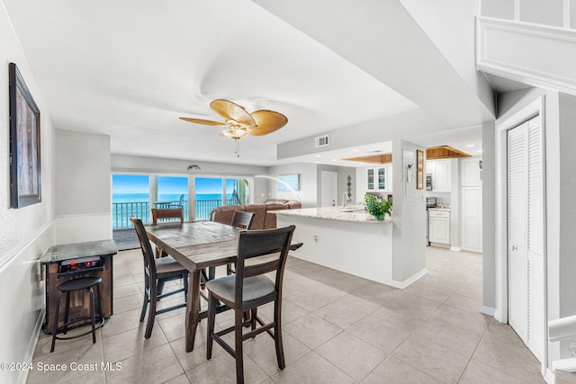 2207 Atlantic St Unit 825, Melbourne Beach, FL 32951 - dining room featuring a water view, a ceiling fan, visible vents, a raised ceiling, and light tile patterned flooring
