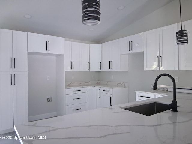 411 La Coco St SW, Palm Bay, FL 32908 - kitchen featuring a sink, light stone countertops, lofted ceiling, white cabinets, and hanging light fixtures
